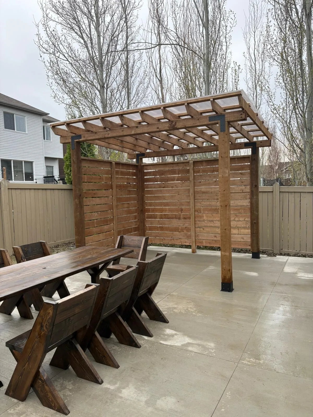 Wood pergola with a privacy wall over a patio, built by Apex Exterior Works